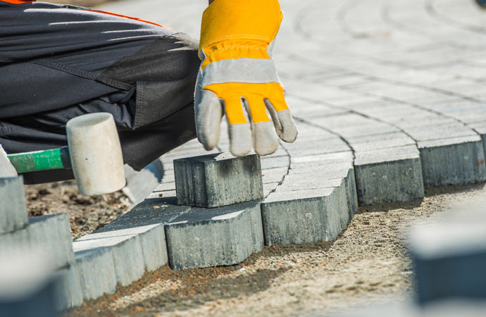Worker installing block paving.